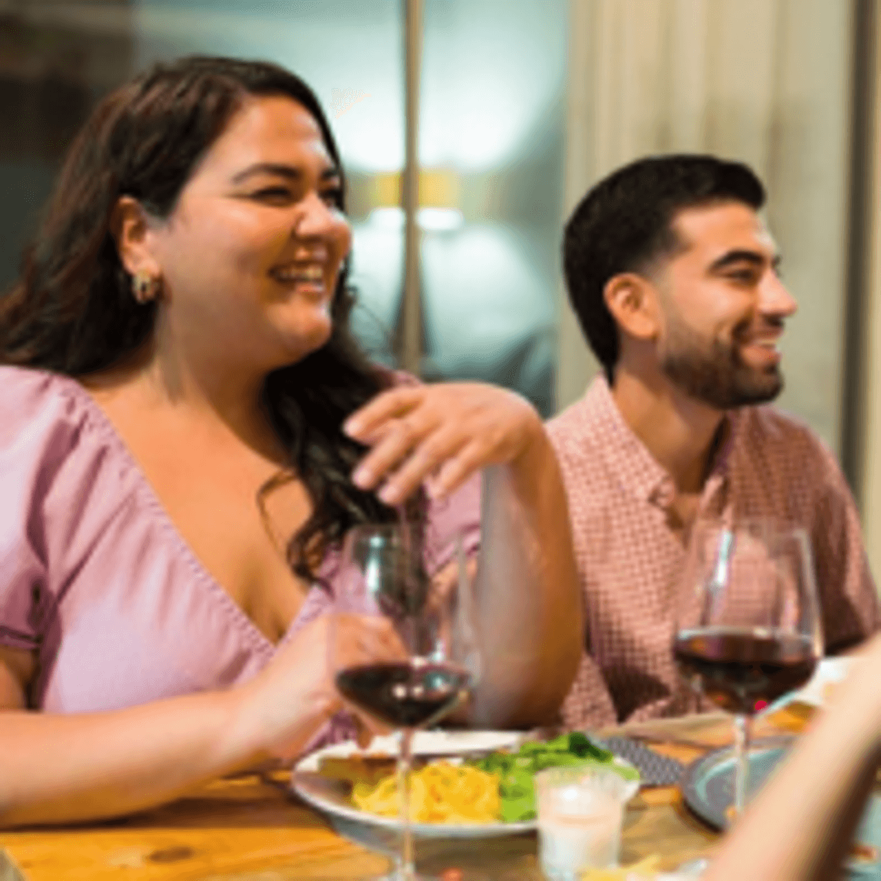 Woman laughing at a table, in a social situation