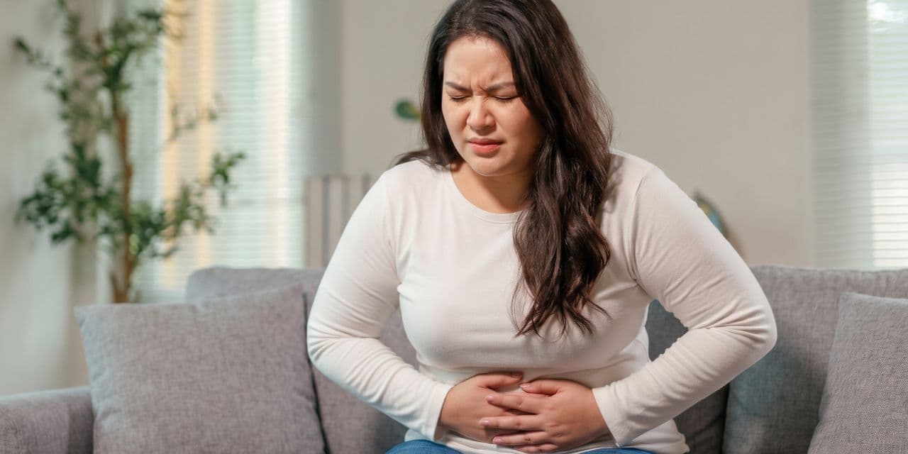 Young woman clutching her stomach, in pain