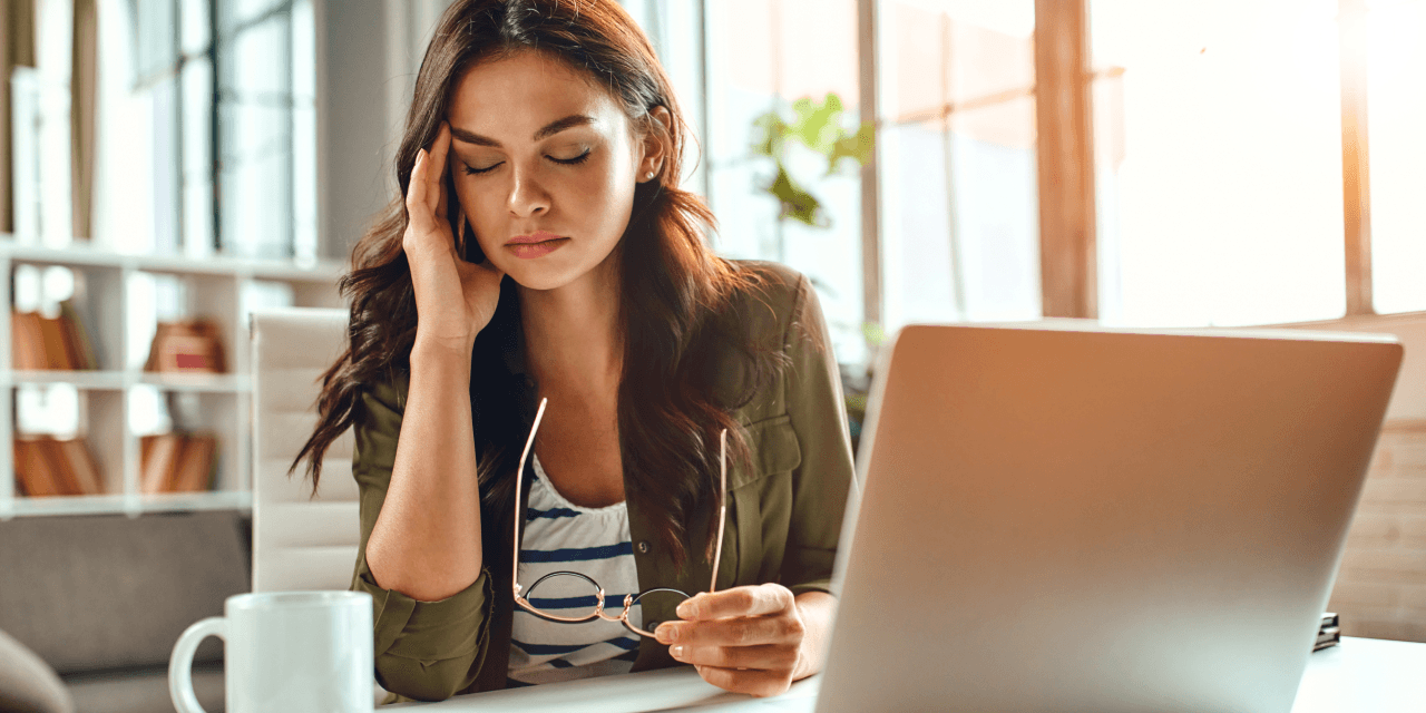 Woman struggling with a headache while working on her laptop