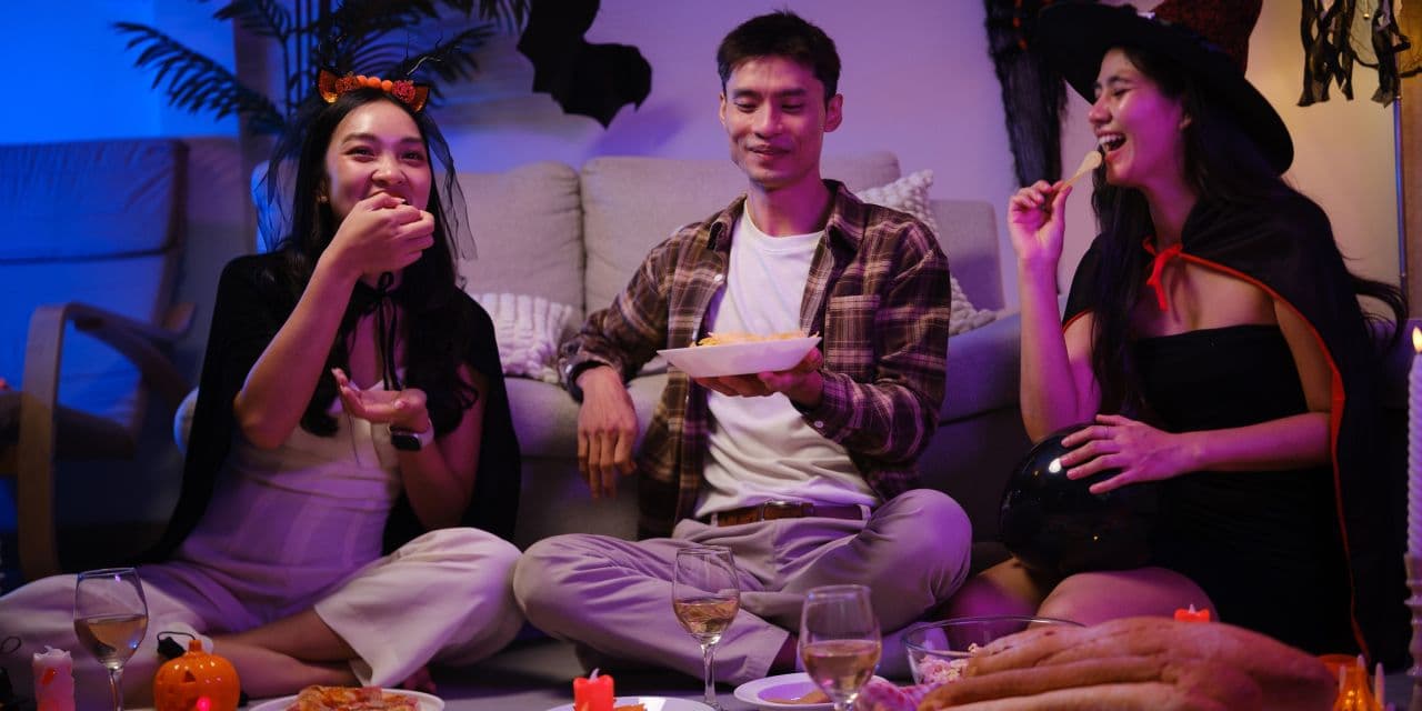 Three friends enjoying Halloween snacks and drinks in costume